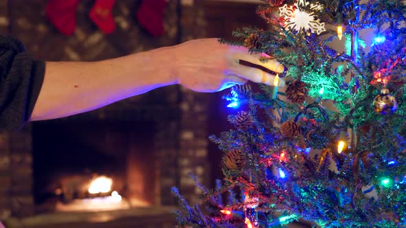 Close up on a family decorating a christmas tree together with lights and ornaments and stockings ov