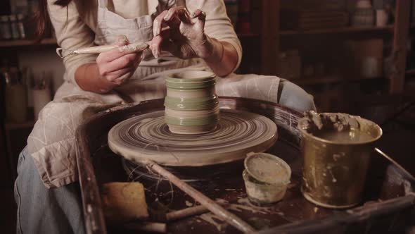 Young Woman Potter Makes Ribbed Borders on a Wet Clay Pot Using a Tool