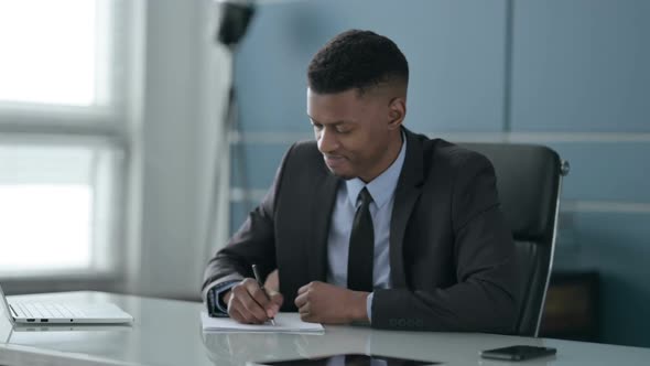 African Businessman having Disappointment while Writing on Paper