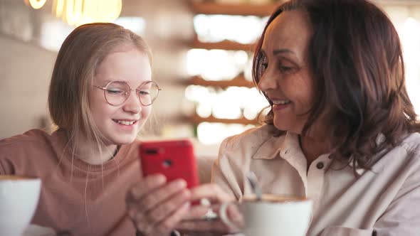 Happy Grandmother and Cute Granddaughter Talking While Sitting at the Cafe