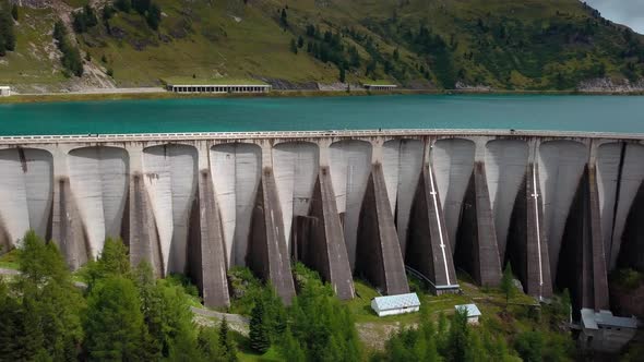 Dam Wall of Lake Fedaia in the Dolomite mountains of northern Italy with people and carsing on the t