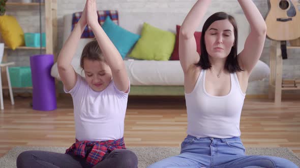 Close Up Mother and Daughter Doing Yoga Sitting on the Floor