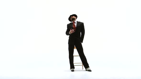 Elegant Man in a Black Hat Is Dancing an Erotic Dance. He Uses a Chair and a Cigarette. White