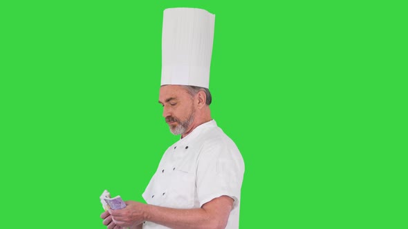 Senior Cook in Uniform Counting Money on a Green Screen Chroma Key