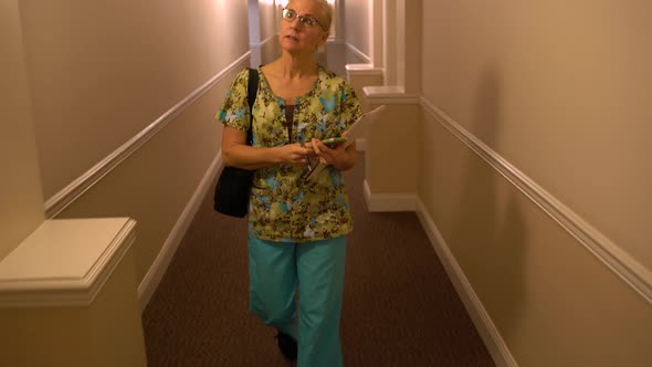 Closeup of home healthcare nurse walking down hallway going to visit a patient in an apartment.