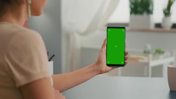 Back View of Freelencer Holding Chroma Key Green Screen Mock Up Smartphone