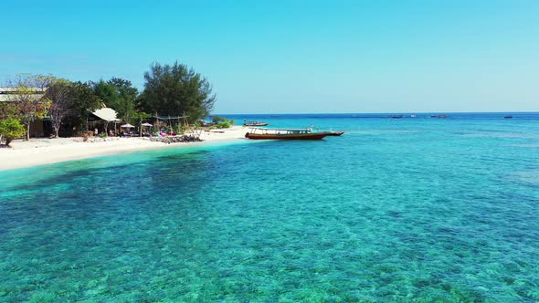 Tropical flying travel shot of a sunshine white sandy paradise beach and aqua blue ocean background 