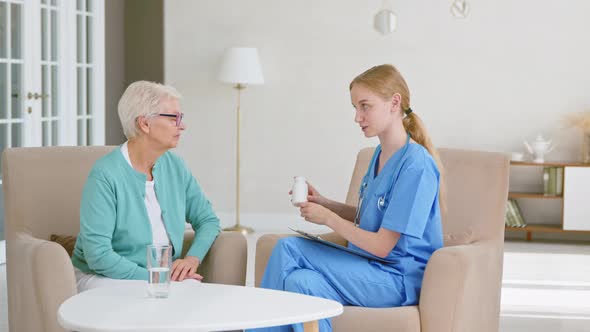 Skilled doctor with ponytail gives bottle of vitamins to senior patient