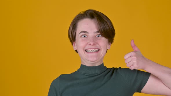 Woman Looking approvingly at camera showing thumbs up, like sign positive something good