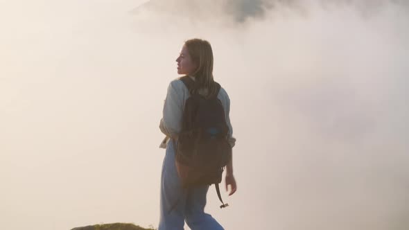 Tourist Student Girl is Walking on Top of Mountain Inside Clouds