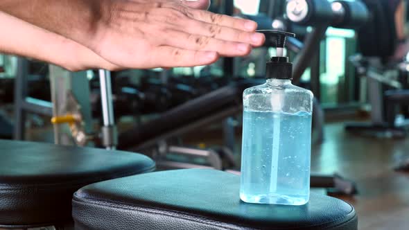 Man Using Alcohol Sanitiser Gel Standing on Fitness Equipment in Gym