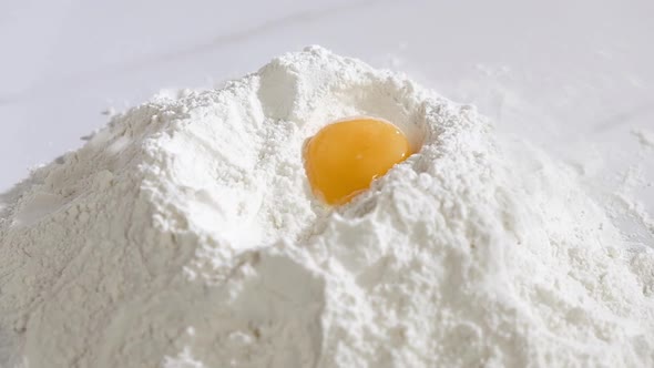 Baker works in kitchen of bakery shop. chicken egg yolk falls into the flour