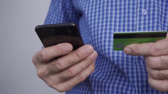 Closeup of Man Hands Holding Credit Card and Using Smartphone