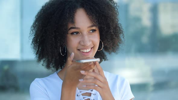 African American Girl Holding Smartphone in Hands, Talking on Speakerphone with Friends, Smiling