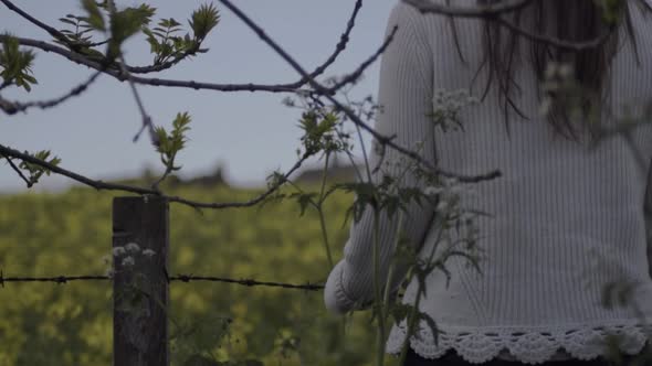 Carefree woman looks at view through field of rapeseed in countryside landscape