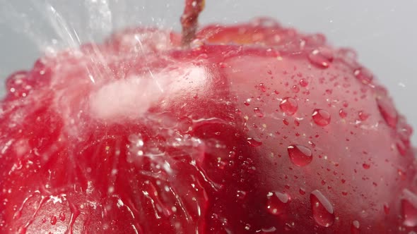 Water being sprayed onto red apple