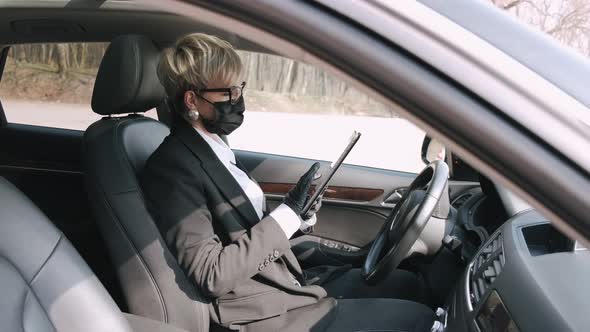 A Businesswoman in Glasses Is Working in a Car