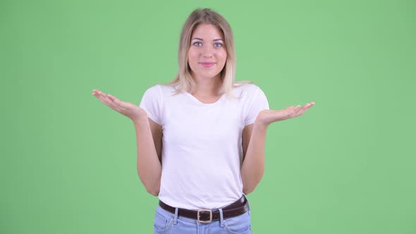 Happy Young Beautiful Blonde Woman Shrugging and Looking Guilty