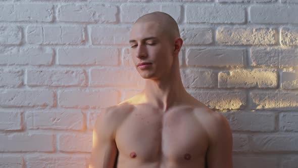 Young Bald Shirtless Handsome Homosexual Man Posing Over the White Wall