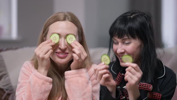 Laughing Young Women Talking in Slow Motion Having Fun Applying Cucumber on Eye Skin