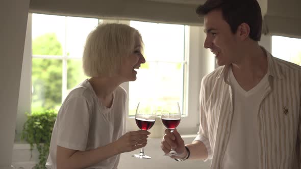 Young Couple in Love Sitting in the Kitchen Flirting and Drinking Wine