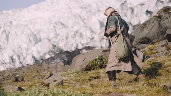 Traveller Carrying Guitar Case On Rocky Hill Next To Glacier