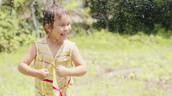 Little Girl Dancing Under the Spray From a Garden Hose