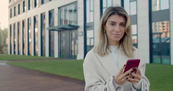 Portrait of Beautiful Young Woman with Blond Hair Using Smartphone and Looking To Camera. Crop View