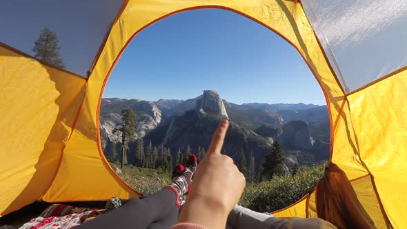 Two People Rest in a Tent Overlooking the Yosemite Valley.They Point Their Fingers at Half Dome Rock