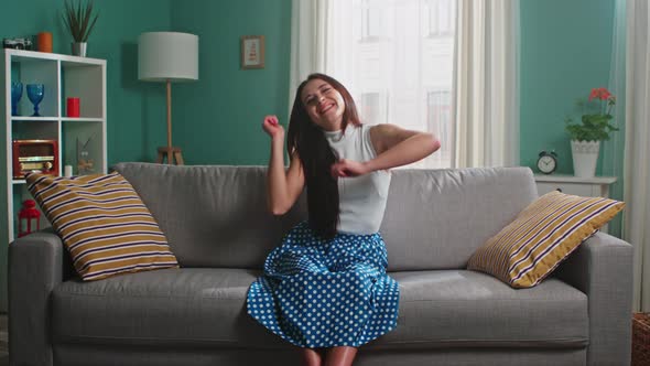 Young Woman Is Sitting On Sofa and Dancing