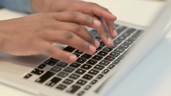 Hands of African Man Typing on Laptop Keyboard Close Up