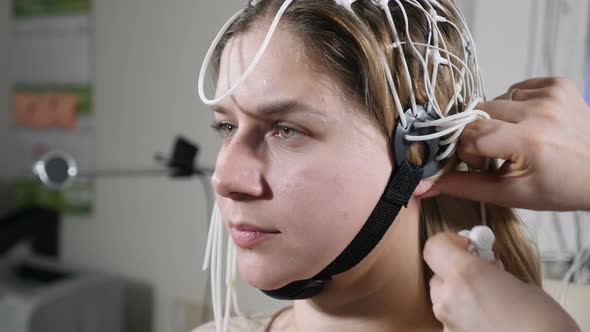 Young Woman Attending Clinic for Neurological Evaluation Using EEG Machine. Female Doctor Operating