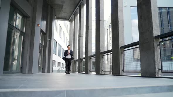 young successful asian businessman walking along the corridor of a modern office building 