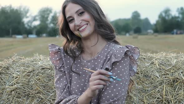 Happy female artist stands in a field on a summer sunset evening