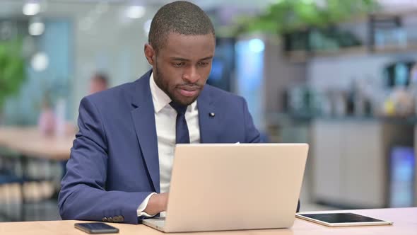 African Businessman with Laptop Doing Thumbs Up in Office
