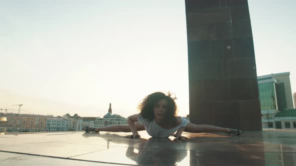 A Young Attractive Woman with Curly Hair Performing Dancing Elements on the Ground - Showing a Split