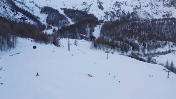 Aerial of people skiing down slope and cable cars on ski lifts at resorts