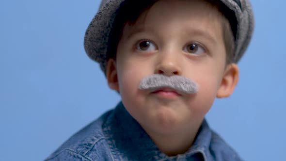 Child with a Gray Gray Mustache and a Hat Stands in the Studio