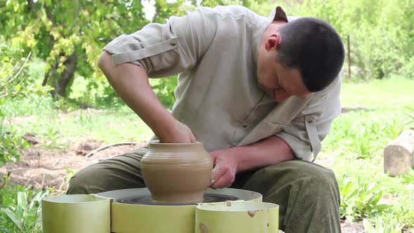 Male Potter Caucasian Ethnicity in a Work Shirt Creates a Large Clay Pot on a Round Rotating Machine