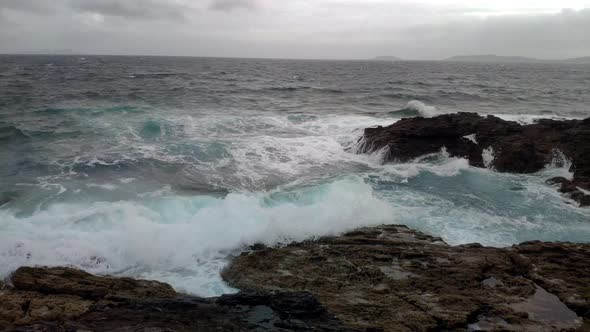 the sea on a windy and cloudy day with waves frothing against the rocks, dark storm clouds. Slow mot