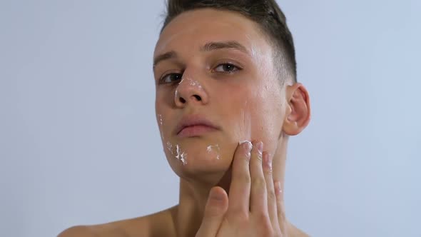 Man Applying Moisturizing Cream on Face and Smiling, Home Spa Treatment Skincare