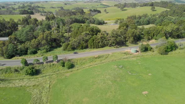 A car parked on a country road in the green hills of the Strzelecki ranges Australia.