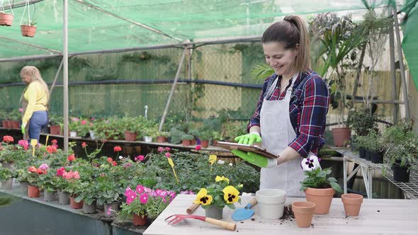 Happy woman working with digital tablet in flower garden shop