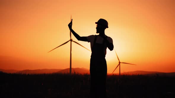 Silhouette Positive Engineer in Uniform and Helmet Using Modern Smartphone for