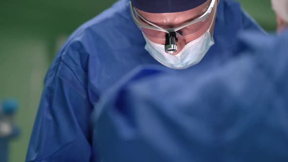 Front View Portrait of Focused Caucasian Surgeon Operating Patient in Slow Motion Looking Down