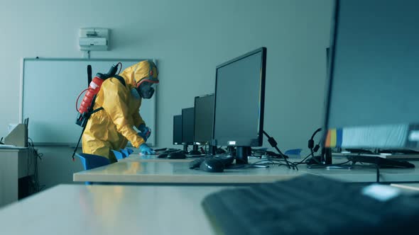 Worker Cleans Desks with Monitors To Kill Virus.