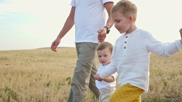 Family with Young Sons Walks in Ripe Wheat Field in Summer