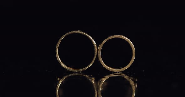 Wedding Rings on Dark Water Surface Shining with Light