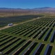 Aerial Over Solar Panel Field, with Mountains and Wind Turbines in Background - VideoHive Item for Sale