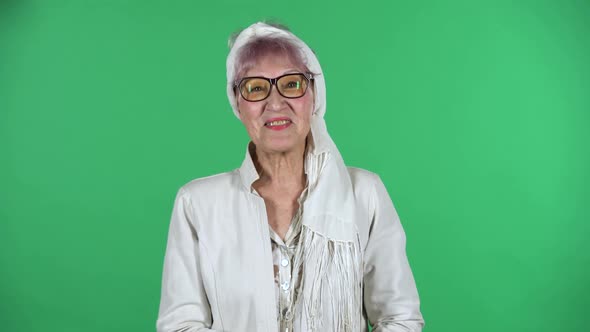 Portrait of Old Stylish Woman Is Waving Hand and Showing Gesture Come Here Isolated Over Green